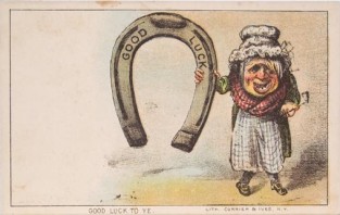 Old Person Standing To Right Holding Enlarged Horseshoe With "Good Luck" Stamped On It