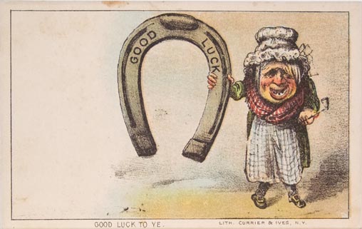Old person standing to right holding enlarged horseshoe with "Good Luck" stamped on it