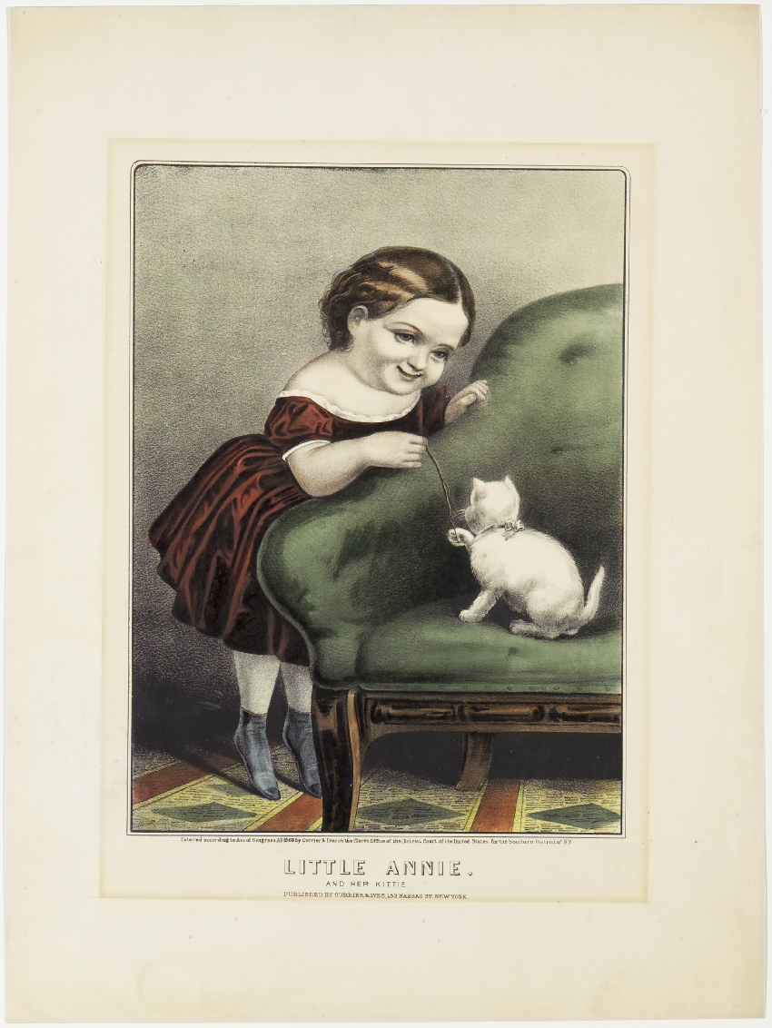 Young girl in red dress leaning over green couch holding onto string white kitten is playing with