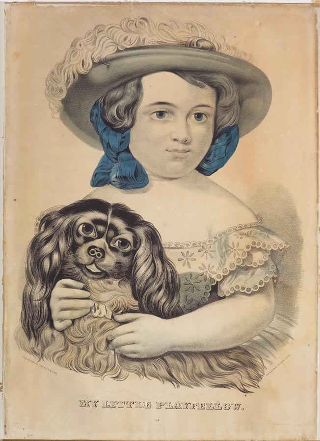 Young girl wearing hat and blue ribbon in hair holding dog on her lap