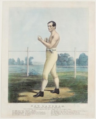 Shirtless Man Standing In Boxing Pose At Center Of Image In A Fenced In Area Facing To Left In Image