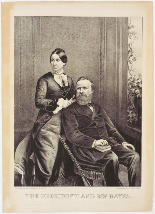 Man On Right Seated With Book On Proper Right Leg And Proper Right Hand On Book