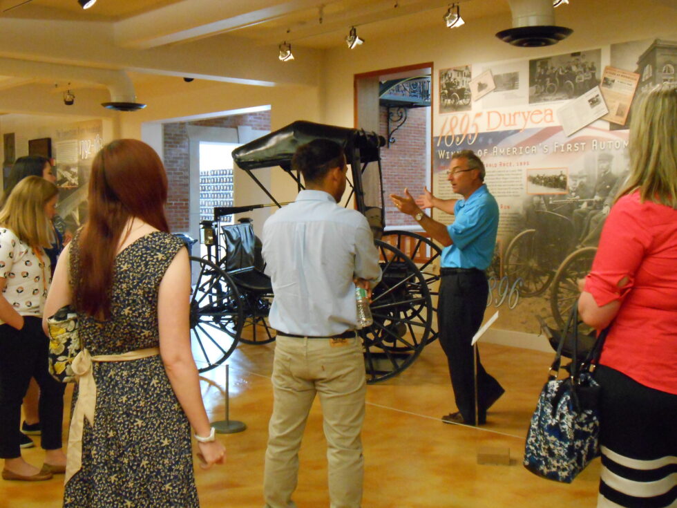 Docent guide discusses antique automobile with students