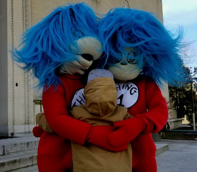 Child hugs costume characters Thing one and two to celebrate Dr. Seuss Birthday