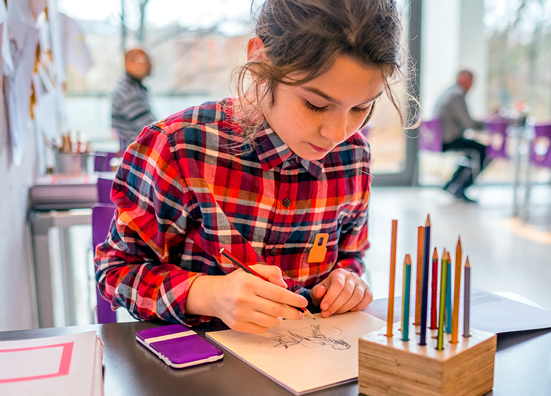 Girl drawing with pencils at a table