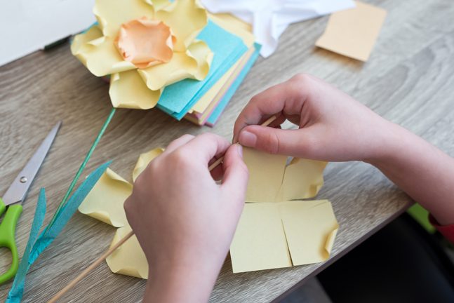 Child's hands making a paper sculpture