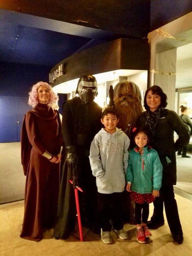 Family of mom and two children standing with costume characters from StarWars