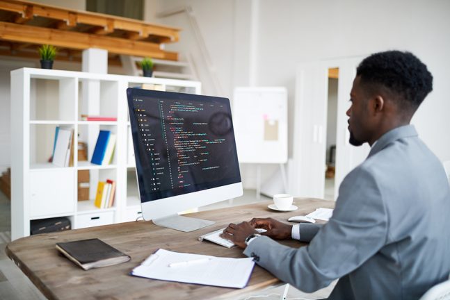 Man seated at desk in front of computer screen