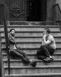 Photo of two men sitting on the steps of an old building