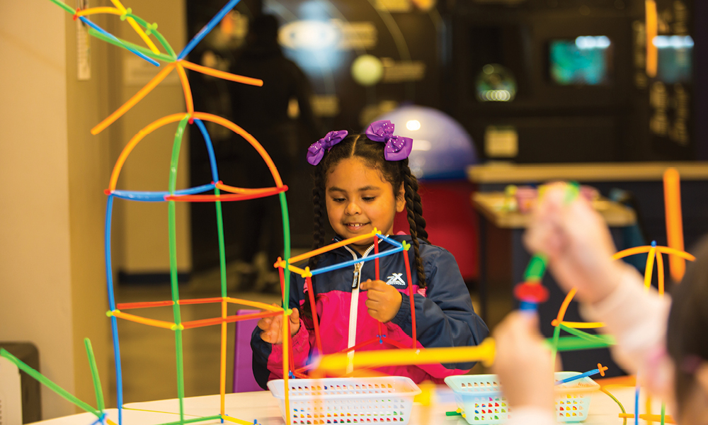 Girl builds a structure with colorful, bendable sticks