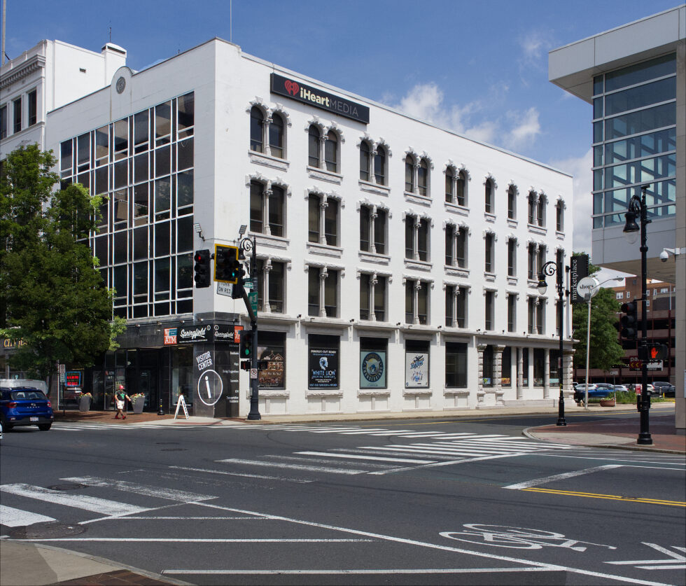 White, four-story building at the corner of an urban intersection