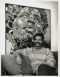 Artist Nelson Stevens seated in front of one of his works