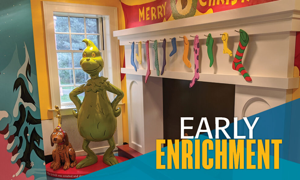 Statue of Dr. Seuss character The Grinch standing next to a fireplace