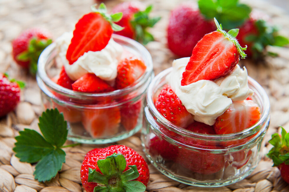 Fresh strawberries and cream in small glass jars
