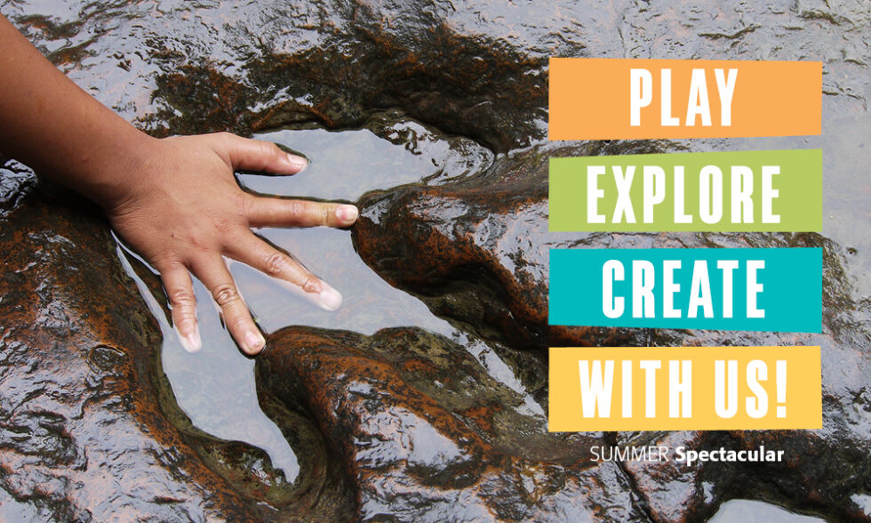 Child's hand touching a dinosaur footprint
