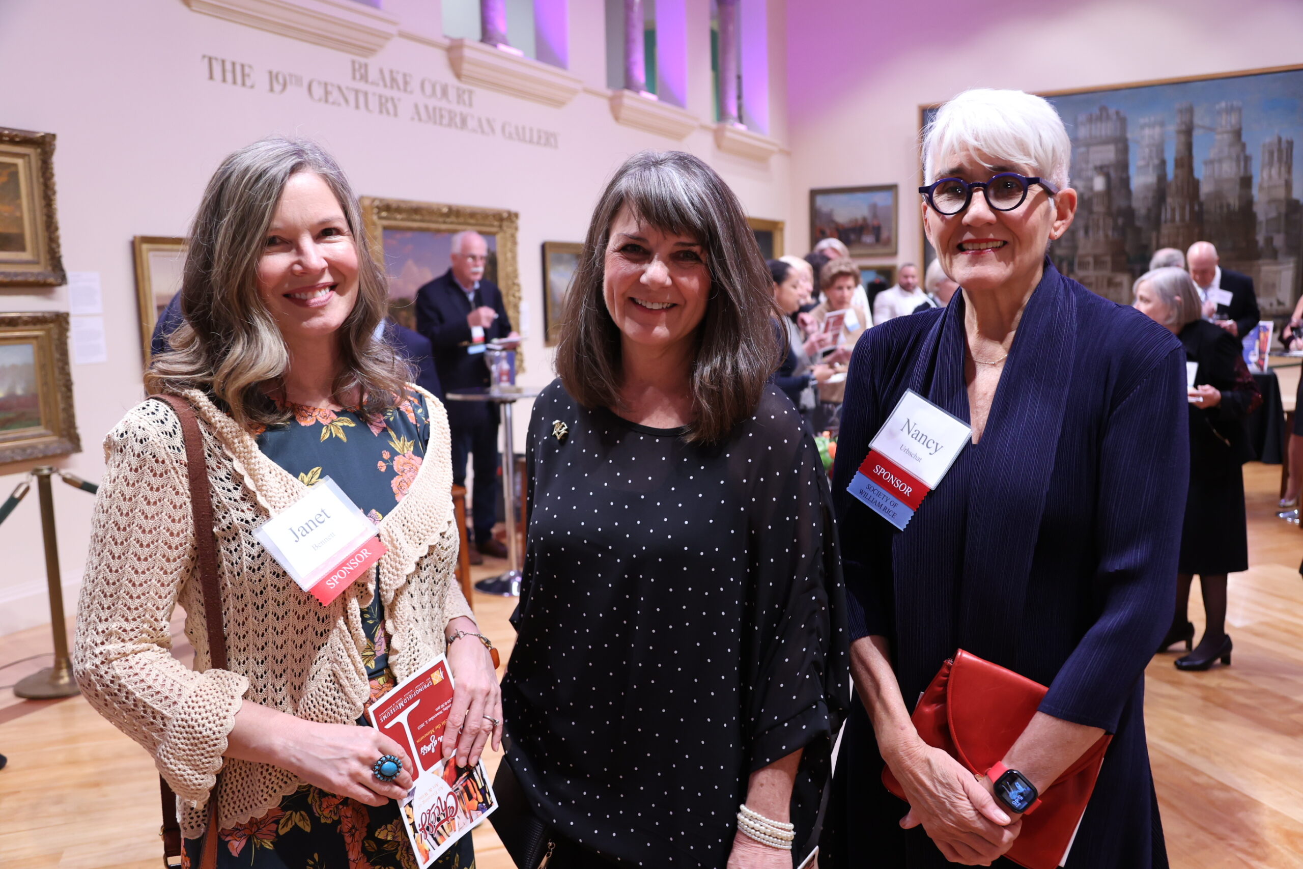 Three people in an exhibit hall smiling for the camera