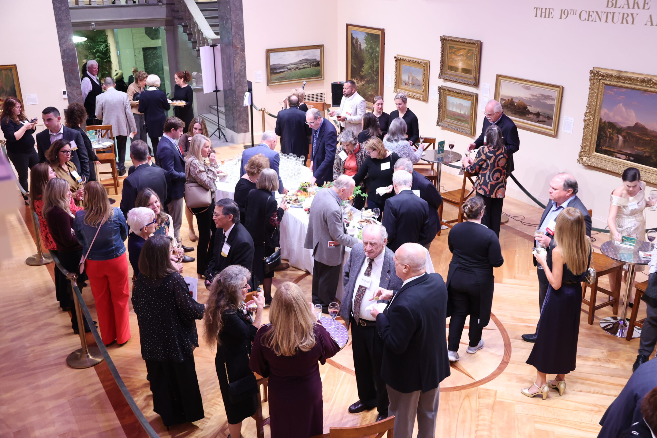 Aerial perspective of people in the Blake Court hall conversing, drinking, and eating
