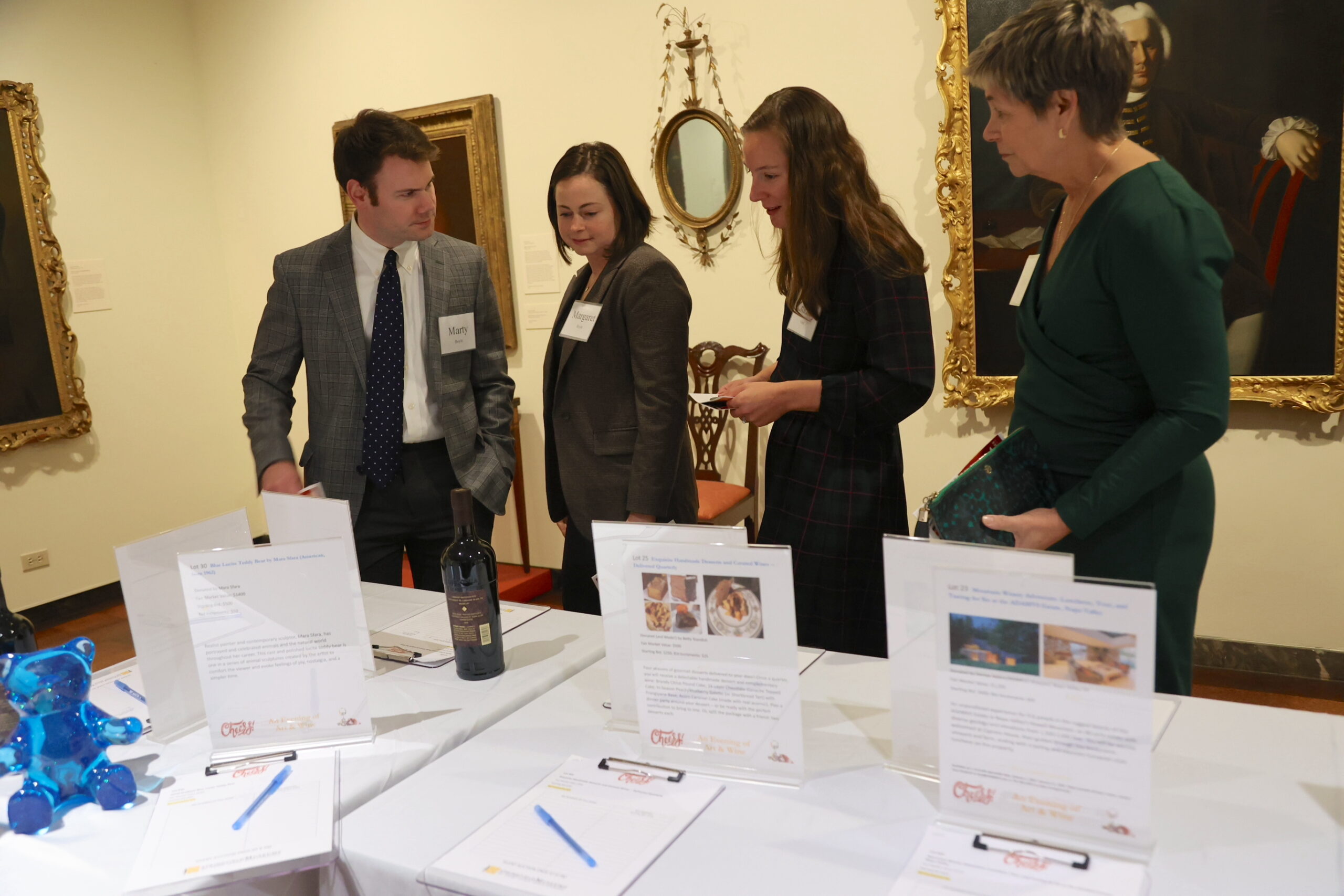 Four people looking at tables of silent auction items in an exhibit hall