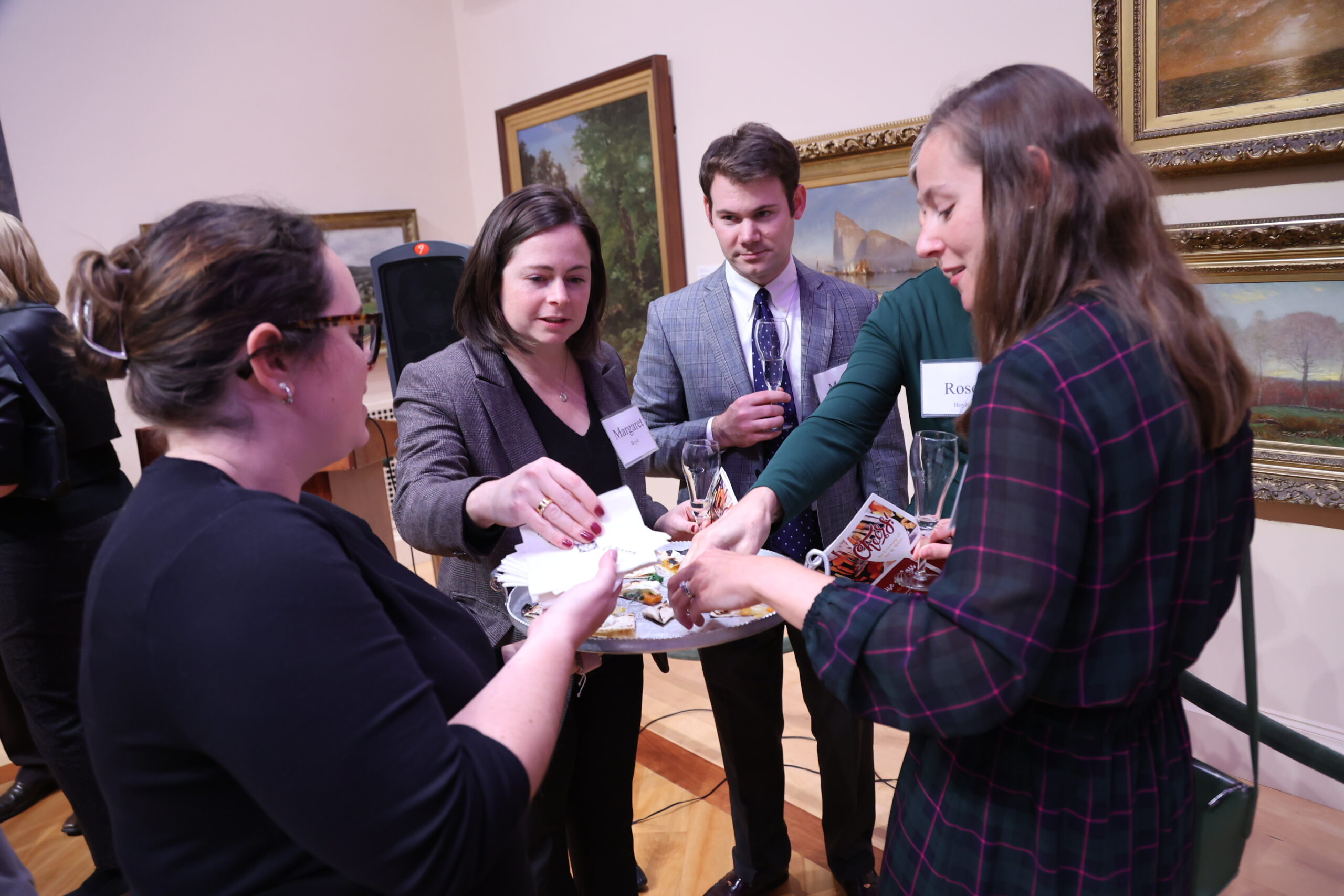 Four people reaching for a platter of hors d'oeuvres that someone is holding