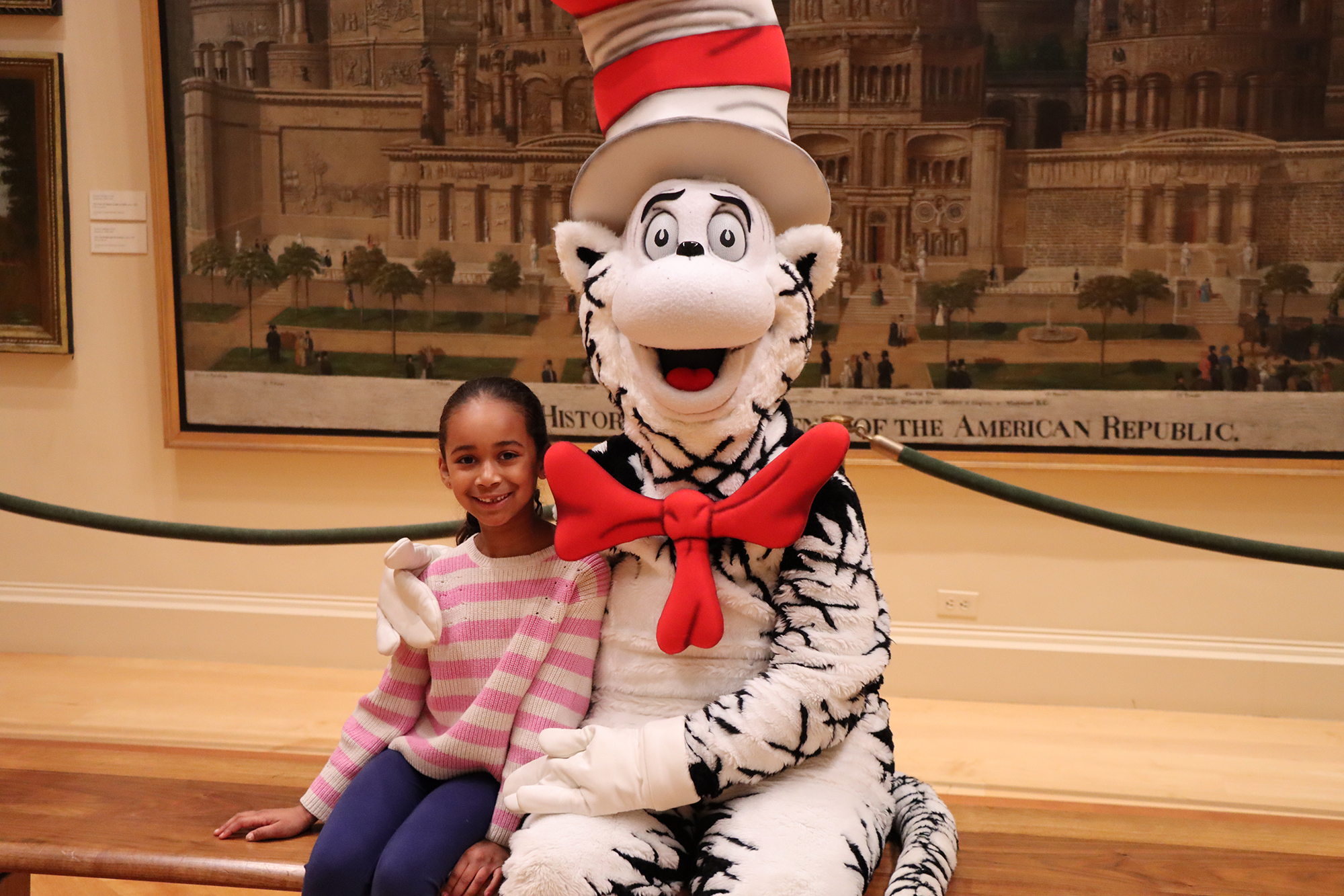 Girl sits next to costume character