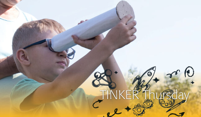 Boy looking through a telescope made of cardboard
