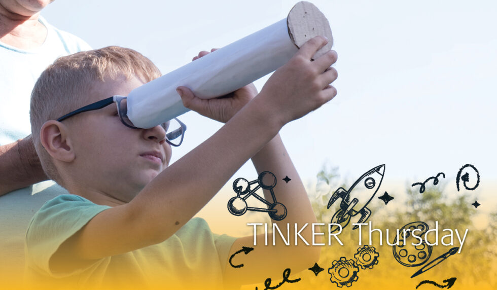 Boy looking through a telescope made of cardboard