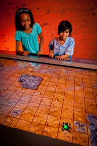 Visitors control the movements of a virtual Curiosity rover on a flat tabletop touchscreen