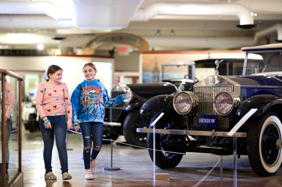 Two girls next to a vintage Rolls Royce automobile