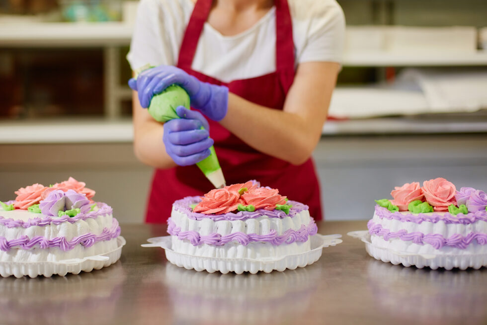 A pastry chef makes flowers from cream to decorate cakes.