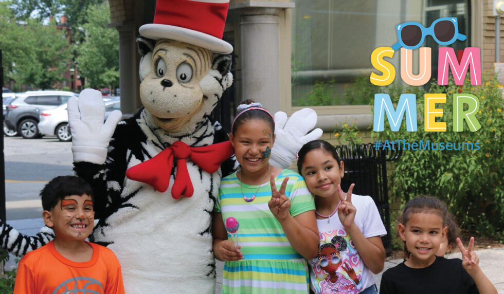 four children posing with the Cat in the Hat costume character