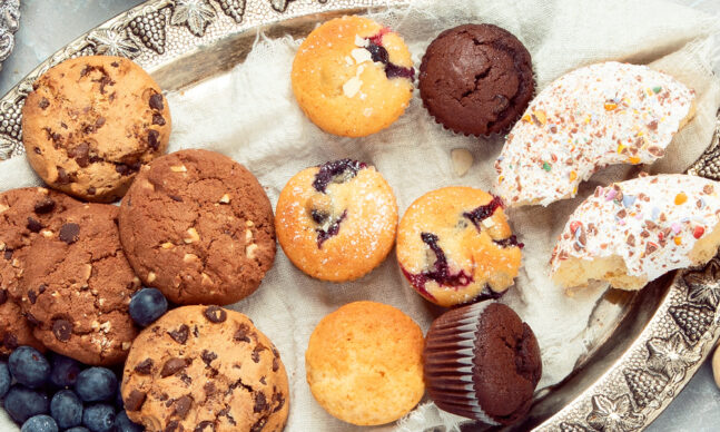 Assortment of cookies and muffins on a silver platter.