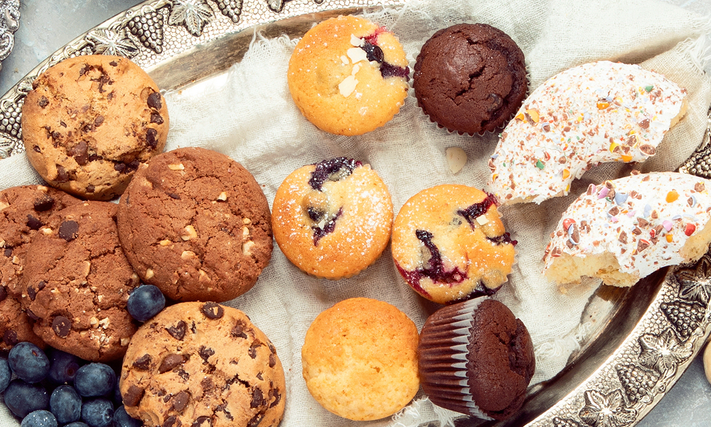 Assortment of cookies and muffins on a silver platter.